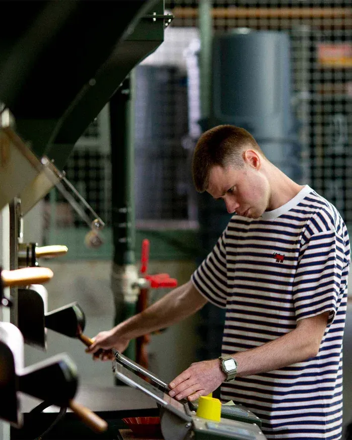 Competitor at the roaster, reading the log while pulling the sample trier